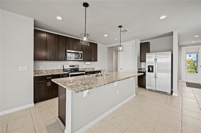 kitchen with pendant lighting, an island with sink, light tile patterned floors, sink, and appliances with stainless steel finishes