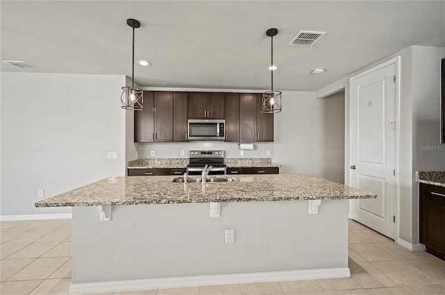 kitchen with hanging light fixtures, an island with sink, stainless steel appliances, and a breakfast bar