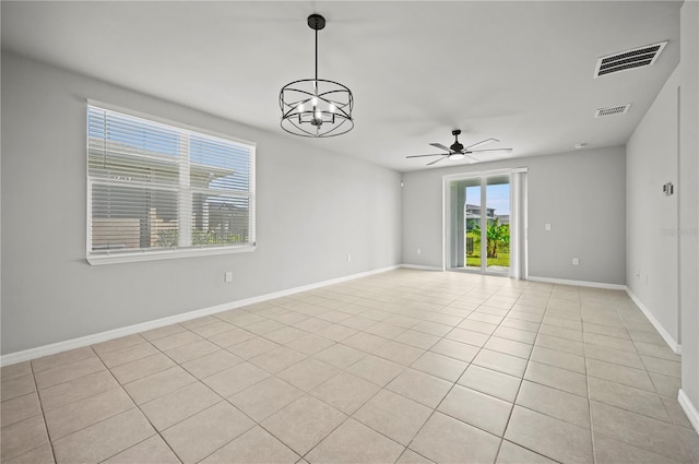 tiled empty room with ceiling fan with notable chandelier