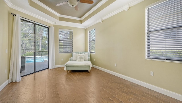 unfurnished room with crown molding, hardwood / wood-style floors, ceiling fan, and a raised ceiling