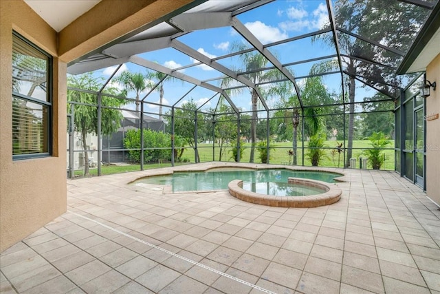 view of pool with a patio, glass enclosure, and an in ground hot tub