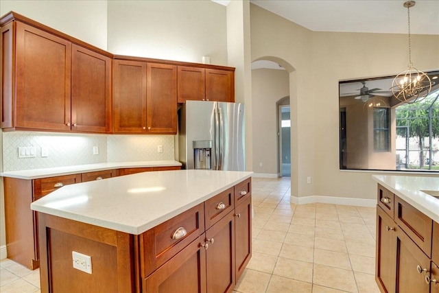 kitchen featuring decorative backsplash, light tile patterned flooring, ceiling fan with notable chandelier, pendant lighting, and stainless steel fridge with ice dispenser