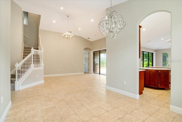 unfurnished room featuring vaulted ceiling, an inviting chandelier, and light tile patterned floors