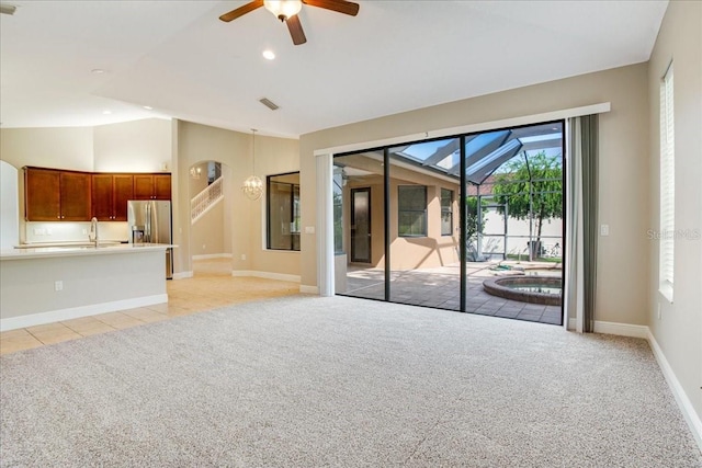 unfurnished living room featuring vaulted ceiling, ceiling fan, light colored carpet, and sink