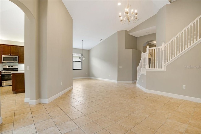 unfurnished living room featuring an inviting chandelier, lofted ceiling, and light tile patterned floors