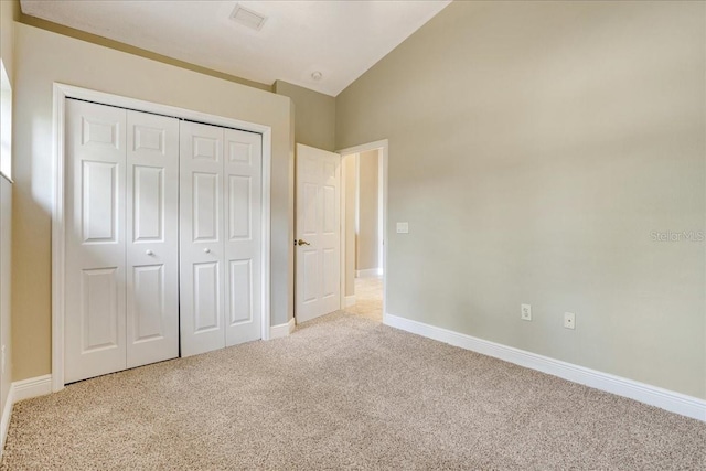 unfurnished bedroom featuring light carpet, vaulted ceiling, and a closet