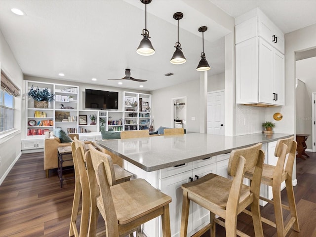 kitchen featuring white cabinetry, dark hardwood / wood-style flooring, a kitchen bar, and hanging light fixtures