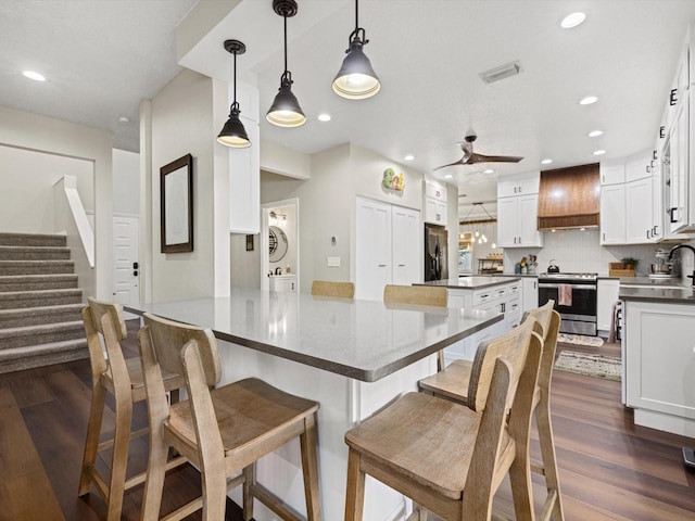 kitchen with white cabinets, hanging light fixtures, premium range hood, dark wood-type flooring, and stainless steel appliances