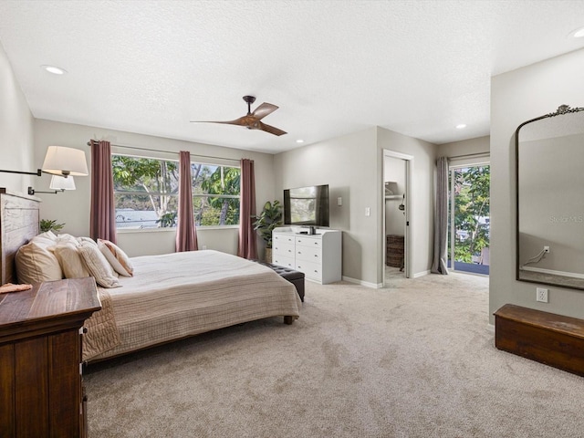 bedroom featuring ceiling fan, a textured ceiling, multiple windows, and light colored carpet