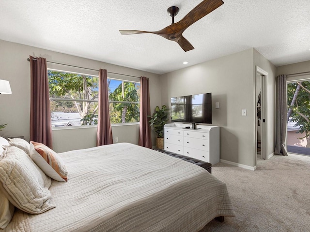 carpeted bedroom featuring ceiling fan, a textured ceiling, and multiple windows