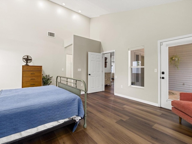 bedroom with a high ceiling and dark wood-type flooring