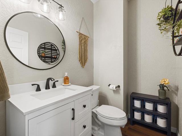 bathroom with toilet, vanity, and wood-type flooring