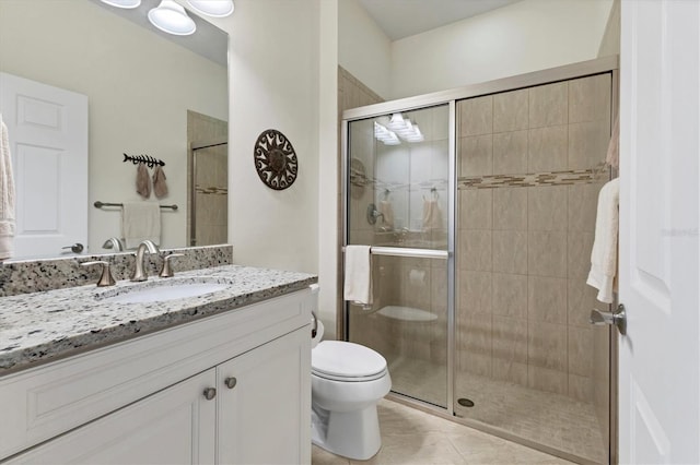 bathroom featuring tile patterned floors, toilet, a shower with door, and vanity