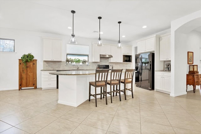 kitchen featuring black appliances, hanging light fixtures, a kitchen island, light stone countertops, and white cabinets