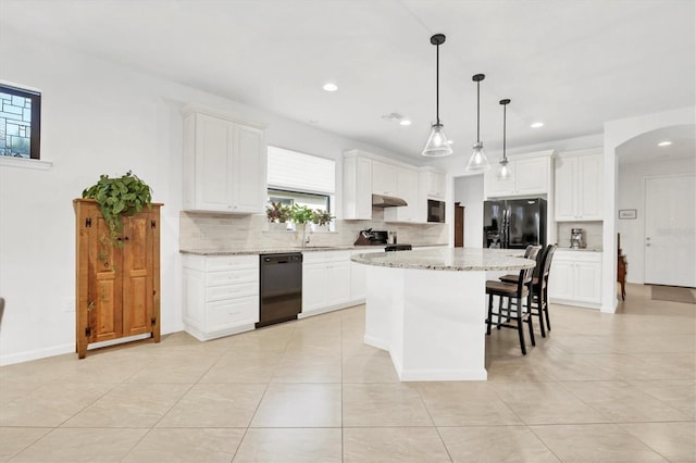 kitchen featuring a kitchen island, pendant lighting, white cabinetry, light stone counters, and black appliances