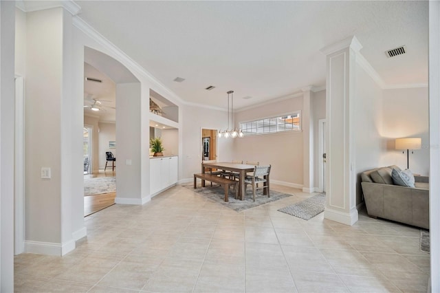 tiled dining area with built in shelves, ceiling fan with notable chandelier, and crown molding