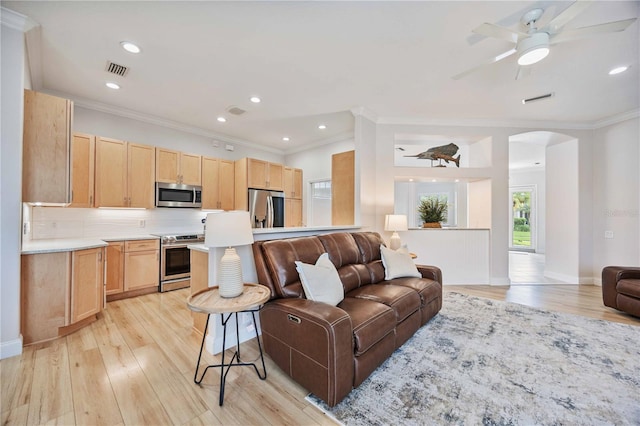 living room with ceiling fan, ornamental molding, and light wood-type flooring