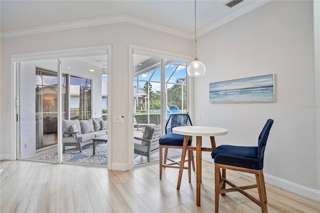 dining space featuring light wood-type flooring and ornamental molding