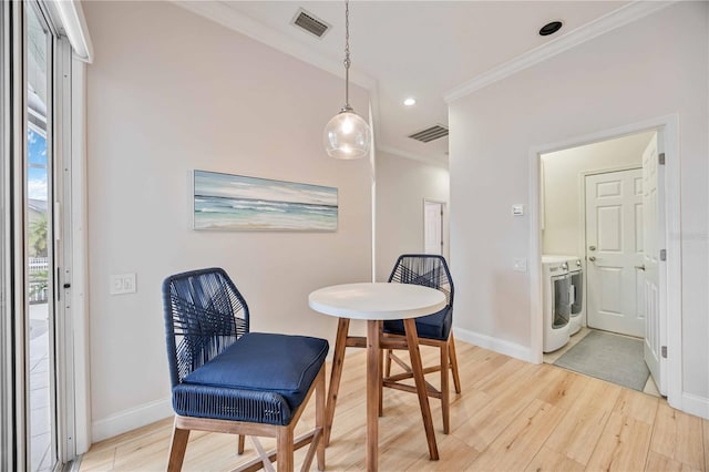 dining space with light hardwood / wood-style flooring, ornamental molding, and washing machine and dryer