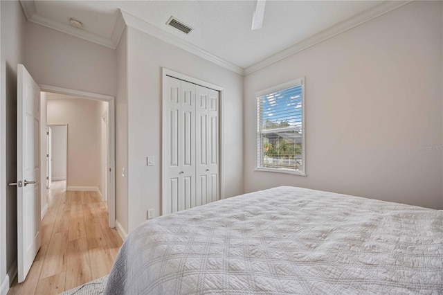 bedroom with ceiling fan, a closet, light wood-type flooring, and crown molding