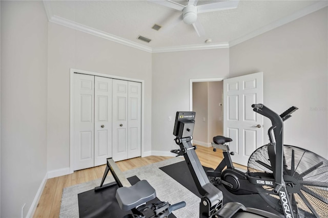 workout room with ceiling fan, crown molding, and light wood-type flooring