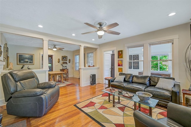 living room featuring decorative columns, ceiling fan, and light hardwood / wood-style floors