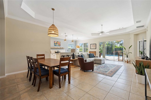 tiled dining area featuring a raised ceiling, ceiling fan, and ornamental molding