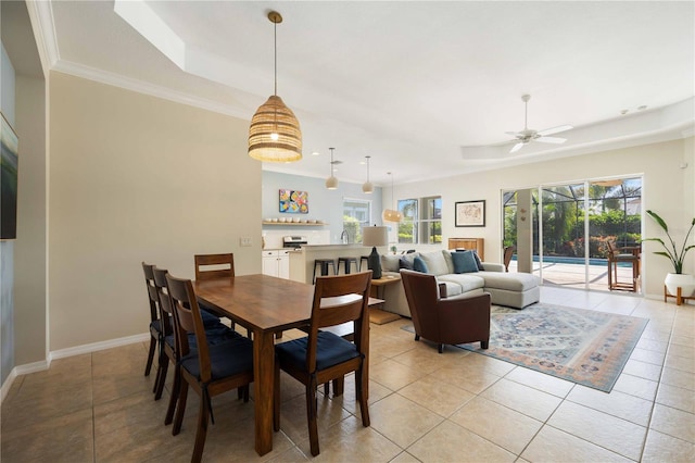 tiled dining room with a raised ceiling, ceiling fan, and ornamental molding