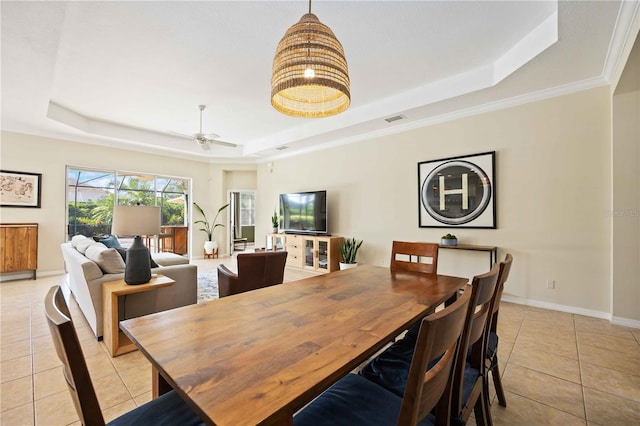 tiled dining room featuring a raised ceiling, ceiling fan, and ornamental molding