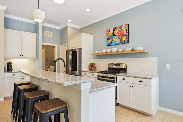 kitchen featuring white cabinetry, stainless steel appliances, backsplash, and an island with sink