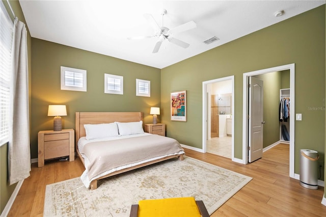 bedroom featuring a spacious closet, ensuite bathroom, ceiling fan, a closet, and light hardwood / wood-style flooring