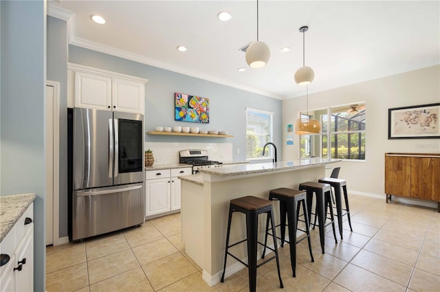 kitchen featuring an island with sink, appliances with stainless steel finishes, light stone countertops, pendant lighting, and white cabinets