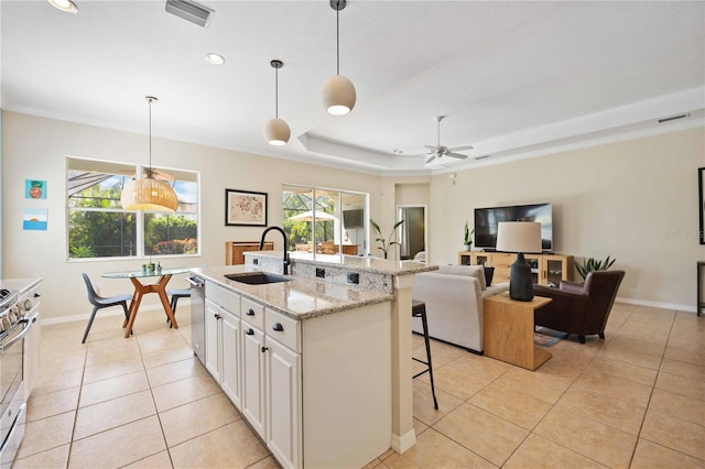 kitchen featuring pendant lighting, a raised ceiling, sink, an island with sink, and white cabinets