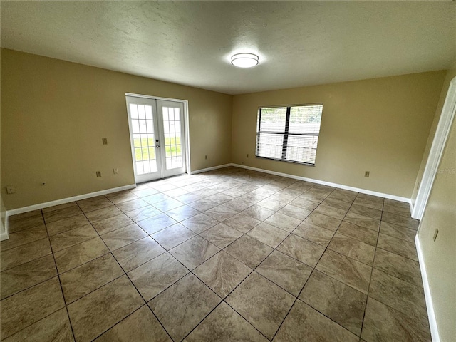 tiled spare room with french doors and a textured ceiling