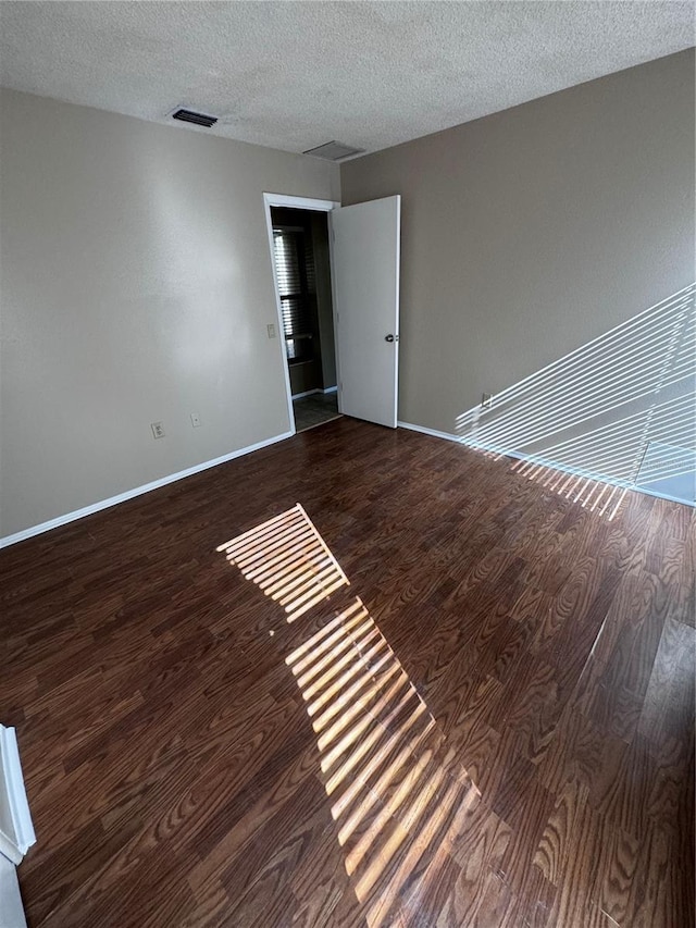 unfurnished room with dark wood-type flooring and a textured ceiling