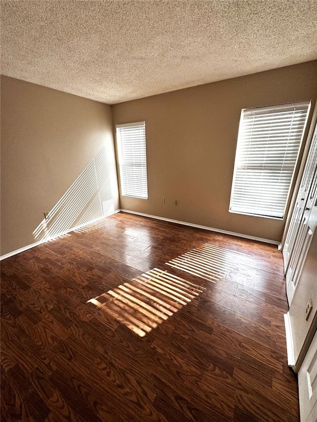 unfurnished room featuring dark hardwood / wood-style flooring and a textured ceiling