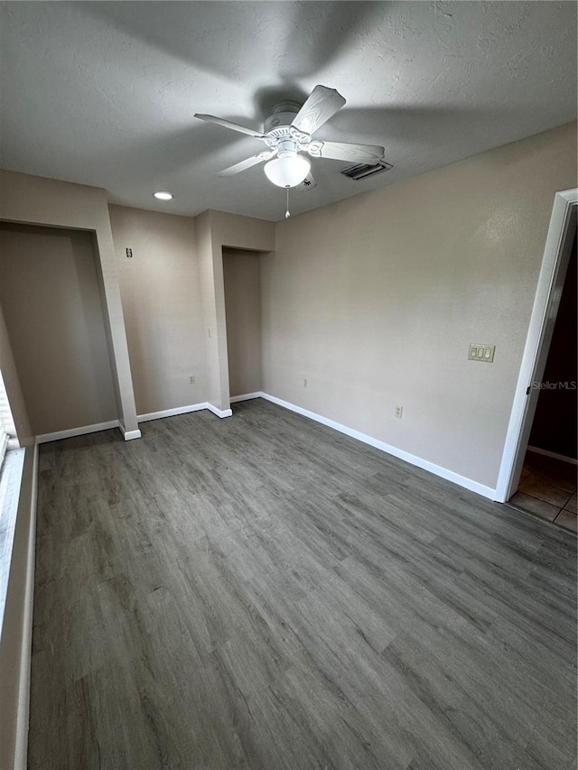 unfurnished bedroom with a textured ceiling, dark hardwood / wood-style floors, and ceiling fan