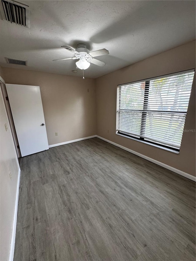 empty room with dark wood-type flooring, a textured ceiling, and ceiling fan