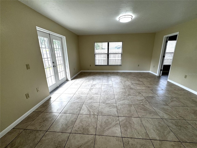 unfurnished room featuring a textured ceiling, light tile patterned floors, and french doors