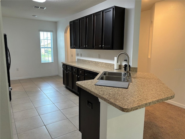 kitchen featuring light tile patterned floors, a kitchen bar, sink, and kitchen peninsula