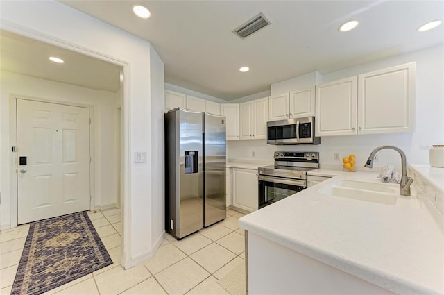 kitchen featuring stainless steel appliances, sink, light tile patterned flooring, and white cabinets