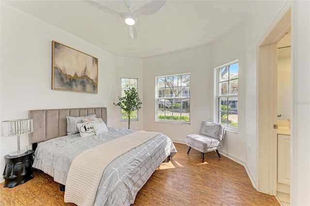 bedroom with connected bathroom, hardwood / wood-style flooring, and ceiling fan