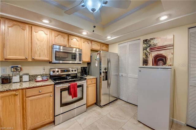 kitchen with a raised ceiling, light brown cabinetry, ceiling fan, and stainless steel appliances