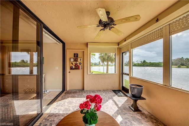 sunroom / solarium featuring ceiling fan and a water view