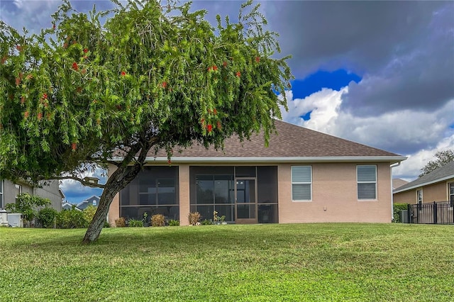 rear view of house with a sunroom and a yard