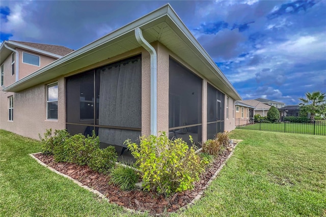 view of property exterior featuring a sunroom and a lawn