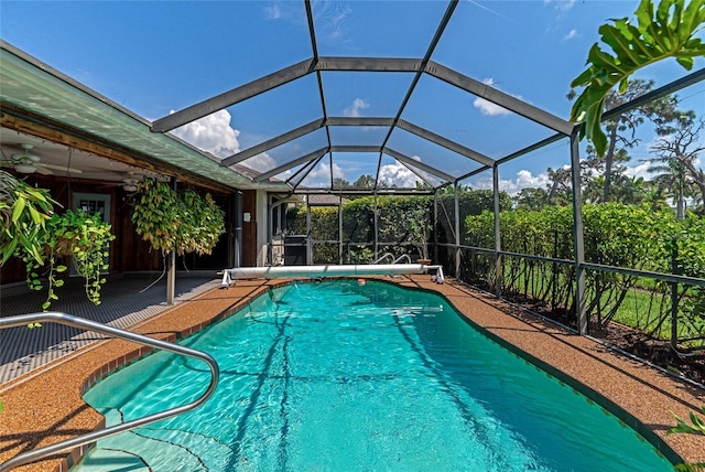 view of swimming pool with glass enclosure, a patio area, and ceiling fan