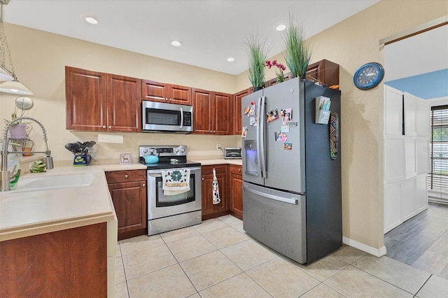 kitchen with appliances with stainless steel finishes, light tile patterned floors, sink, and pendant lighting