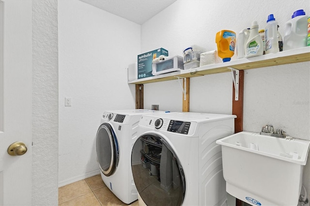 laundry area with washer and clothes dryer, light tile patterned flooring, and sink