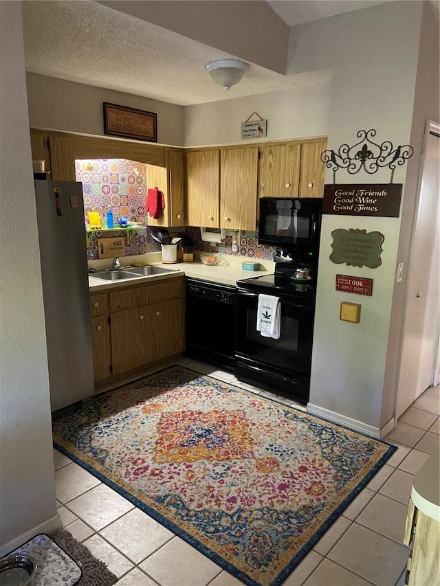 kitchen featuring black appliances, light tile patterned floors, a sink, and a textured ceiling